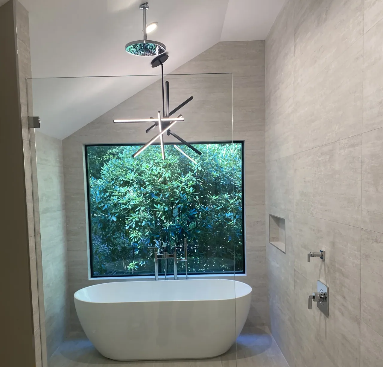 A high-end bathroom renovation with a freestanding tub, frameless glass shower, and large picture window.